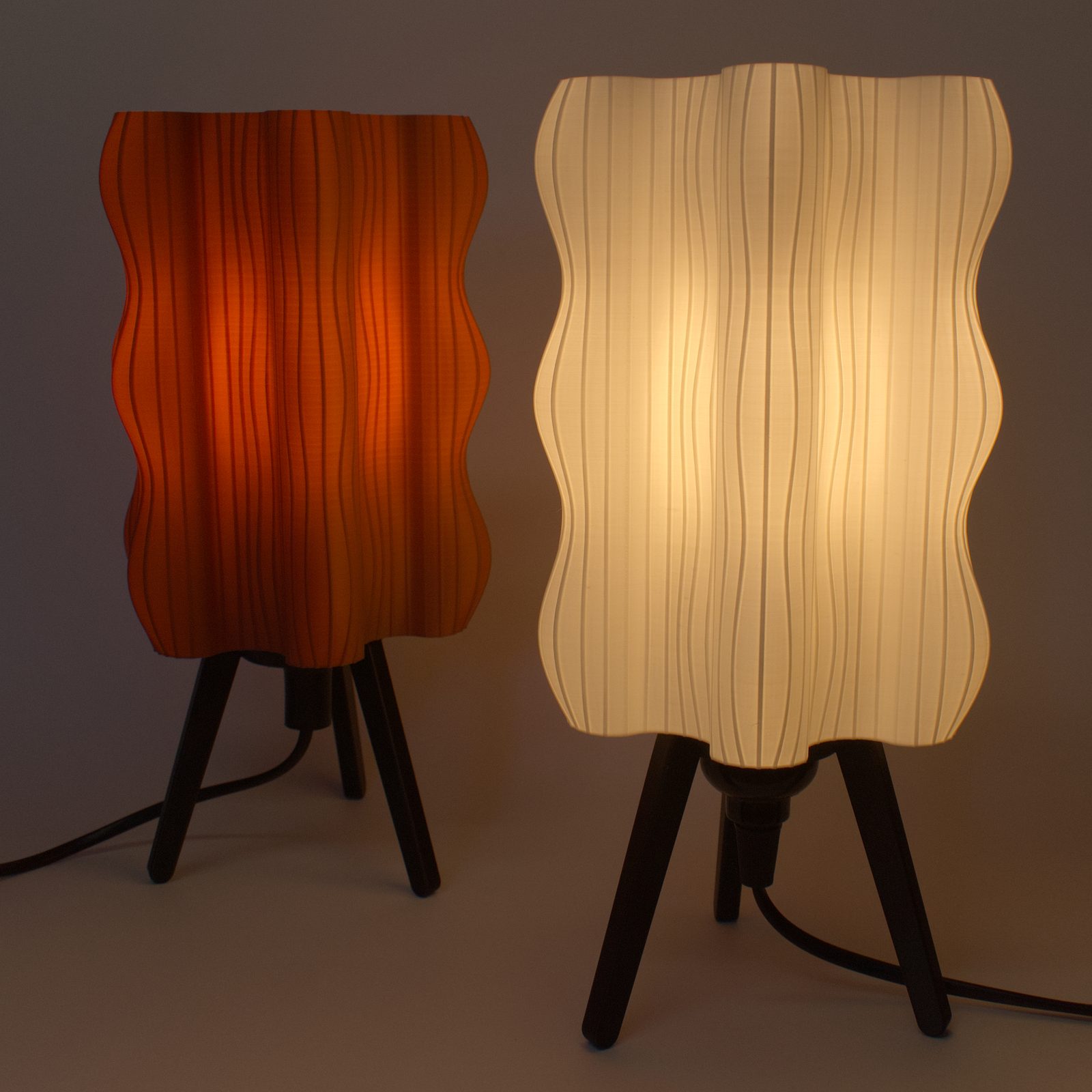 A white and a brown Ripple Lamp glowing side by side